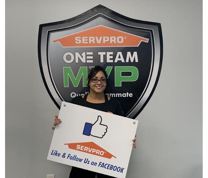 SERVPRO female employee holding a sign that says "Like us on Facebook"
