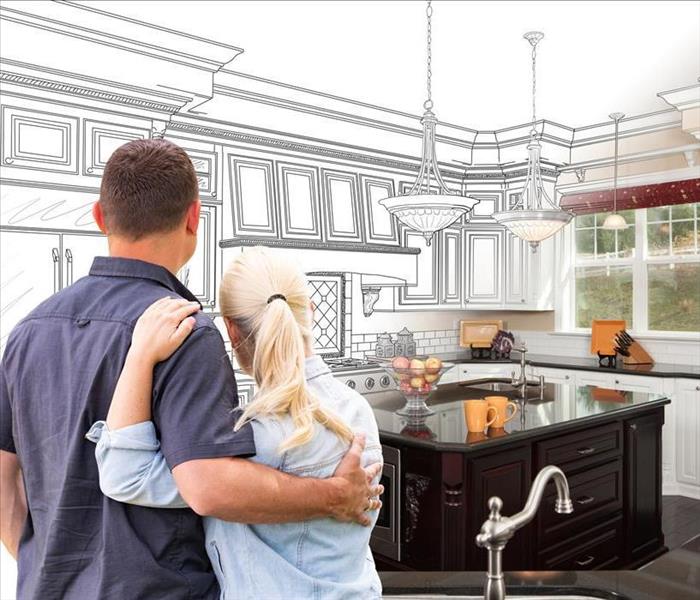 couple from the backview looking at a schematic of a kitchen remodel
